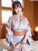 A woman in a blue kimono sitting on a bed.