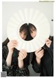 Two young women holding up a white paper fan.