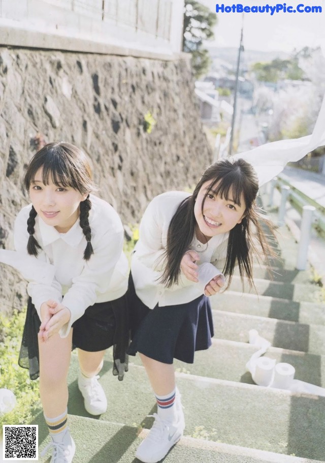 A couple of young women standing next to each other on some steps.
