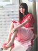 A woman in a pink dress sitting on a window sill.