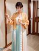 A woman in a long dress and a yellow kimono posing for a picture.