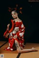 A woman in a red kimono sitting on a tatami mat.